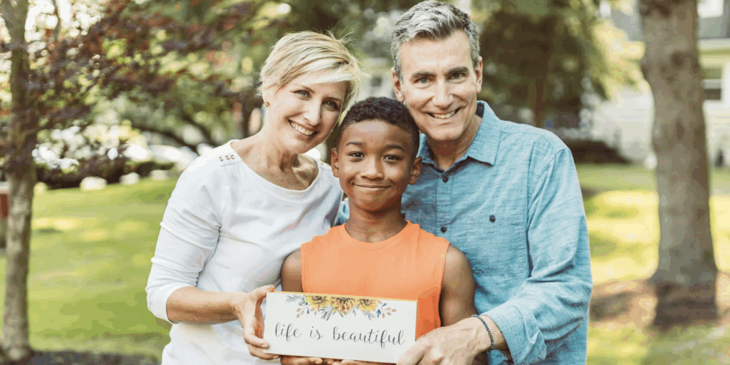 Family holding a sign that reads "life is beautiful," representing love and support in the context of adoption and blended families.